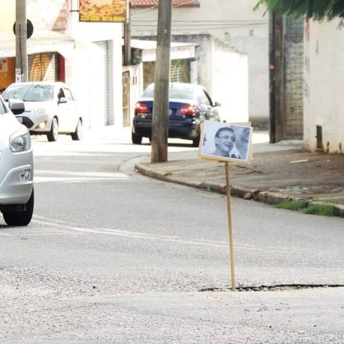 Moradores espalham placas com fotos do prefeito em buracos de rua em cidade paulista